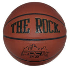 The Rock 2.0 basketball in brown leather with black seams, featuring gold text and a city skyline graphic.