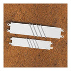 Two white rectangular pitcher's rubbers with attached metal spikes, shown from a top-down angle on a dirt surface.