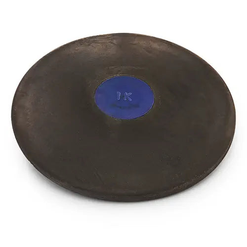 A black Nelco rubber discus with a blue center plate labeled 1K, viewed from a high-angle perspective.