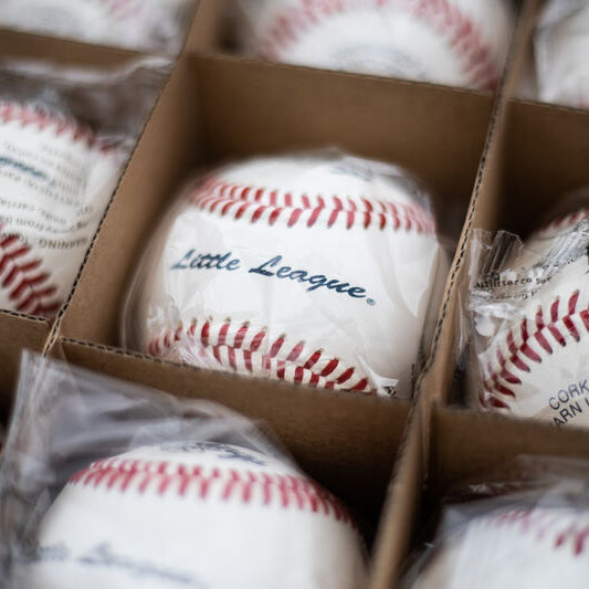 Rawlings RLLB Little League baseballs in individual plastic wraps, neatly organized in a cardboard shipping box.